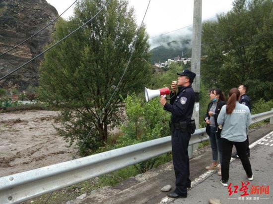 民警用话筒喊话，通知群众转移