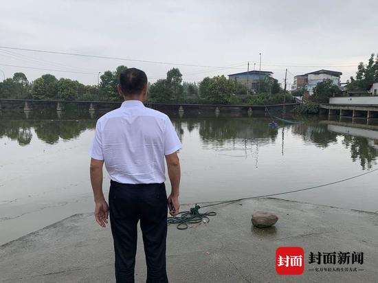 程明富站在魚塘邊