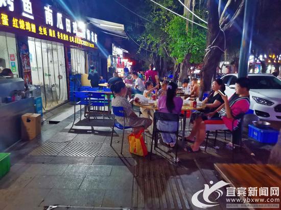 南岸二零二路段的宵夜店,將餐桌擺在了人行道,過往行人無法通行。記者 何東 攝