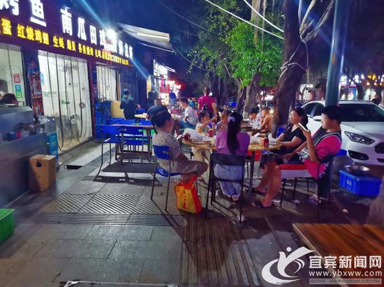 南岸二零二路段的宵夜店，将餐桌摆在了人行道，过往行人无法通行。记者 何东 摄