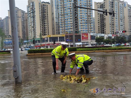 民警徒手清掏堵塞下水道的树叶