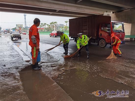 民警与环卫工人一道清理积水