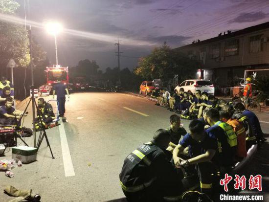 明火完全撲滅后,部分救援人員從火場撤出,在馬路上休息。 單鵬 攝