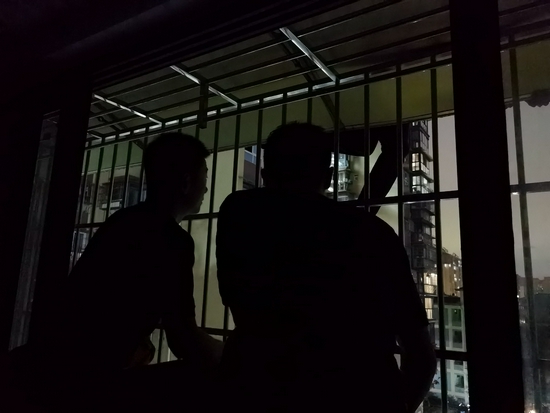 消防救援人员透过防盗窗将两根20米的安全绳索固定在男子悬吊的腿部 高颖摄