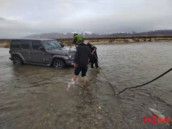 救援人员下河帮助将车拖上岸