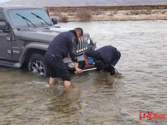 救援人员下河帮助将车拖上岸