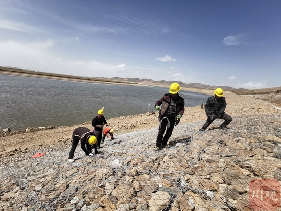 工人在黄河堤岸上进行格宾网石笼护坡的作业。