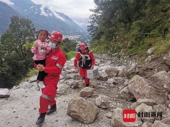 救援队员抱着小女孩，护送受灾群众回家