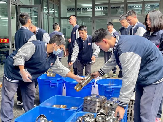 坚守在食堂岗位的同学协助整理餐具