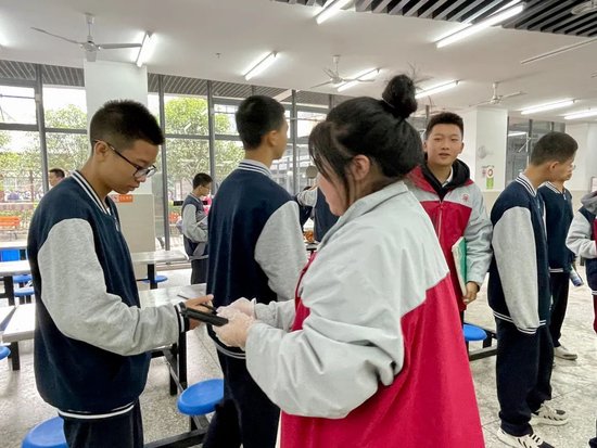 在食堂岗位的同学为其他同学分发筷子