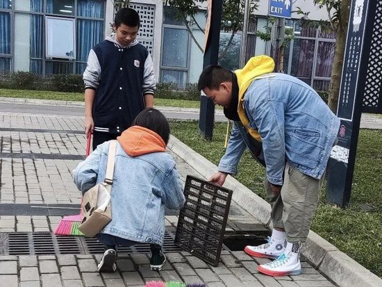 老师和同学们一起清洁下水道的垃圾