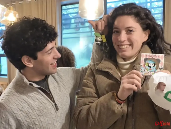 ▲意大利游客Scarlata Giulio（男）与Surico Eleonora（女）展示购买的纪念品