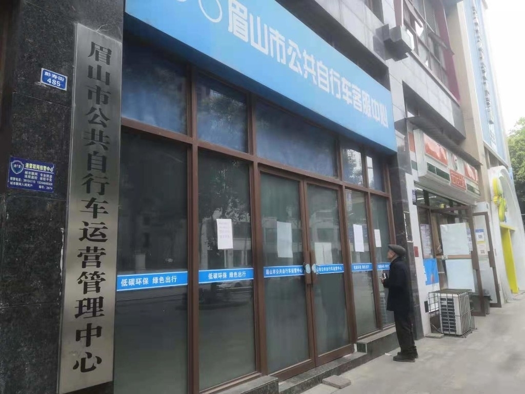 3月19日下午,一位眉山市民正在眉山市公共自行車客服中心門外查看公共自行車退卡須知
