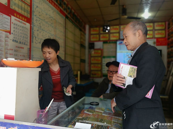 李英平为一名购彩市民打印彩票。(宜宾新闻网 曾江 摄)