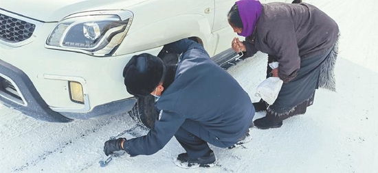 洛戈梁子警务站民警为被困雪地里的汽车安装防滑链 甘孜公安供图