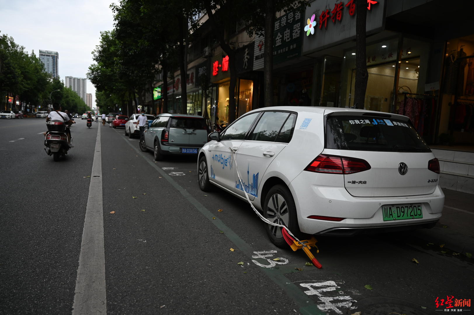 共享汽车占道停车不交费和违章停车。守车工作人员为了防止欠费车开走,将车辆上锁并拴绳子提示。