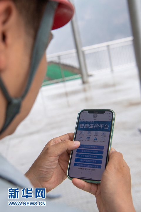 　在白鹤滩水电站，工作人员在手机上通过智能温控平台监测大坝温度（6月9日摄）。新华社记者 胥冰洁 摄