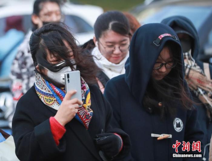资料图:民众在大风降温天气中出行。中新社记者 贾天勇 摄