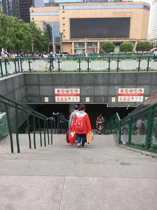 乘客拿着大包小包走下楼梯