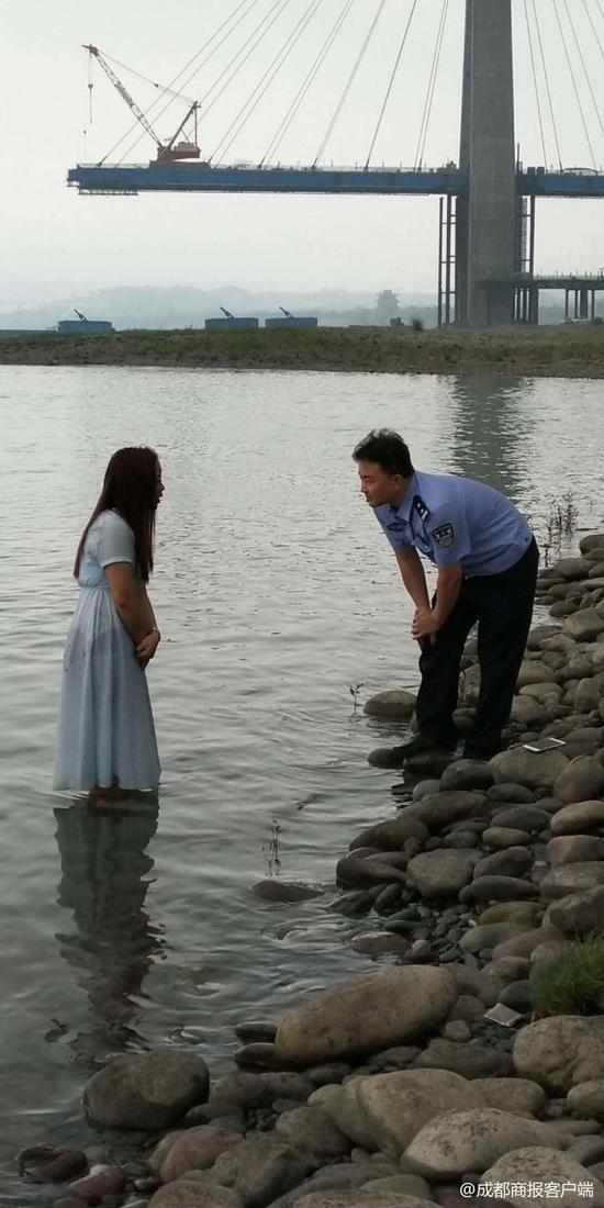 ▲胖警官站在江中的石堆上与女子沟通,她的背后是一片深水区