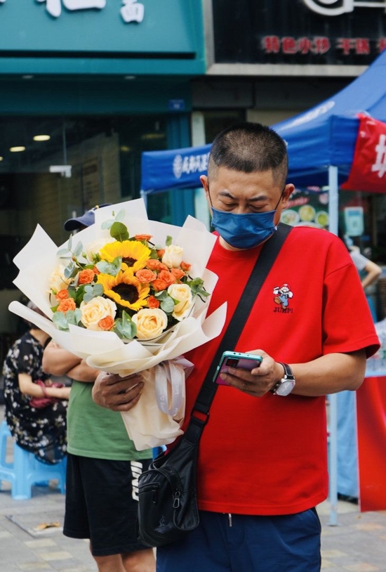 成都市第八中学考点外,家长捧花迎接考生。魏冯 摄