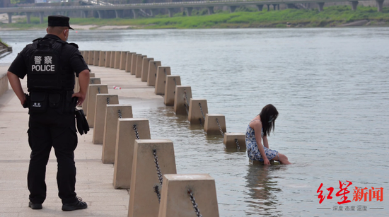 ▲女子坐在江中一个栏杆墩上。