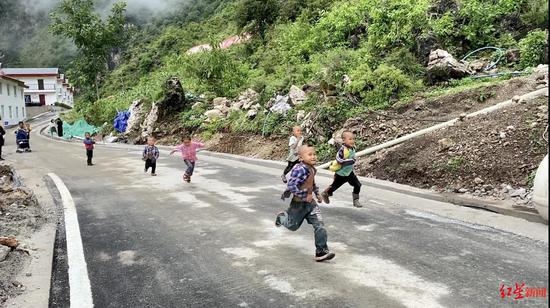 ↑阿布洛哈村的通村公路建成,小孩在奔跑玩耍