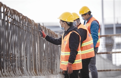 昨日,三環路成仁快速路節點立交工程施工現場,工人戴著安全帽和口罩施工