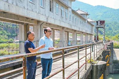 8月17日,武引工程一期现场,四川日报老记者何玉文(左)向川报青年记者王成栋回忆当年的采访情景。