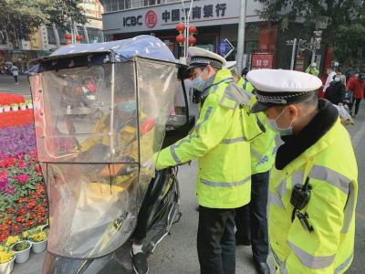 交警對安裝了遮陽傘的電動自行車車主進行安全教育。