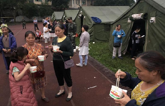 6月18日,在长宁县双河镇中学操场,群众吃上热粥。 新华社发(曾朗摄)