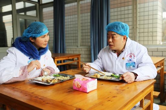 夫妻两人在食堂吃午饭期间,交谈门诊病人情况 张红 摄