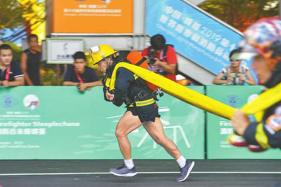 8月10日，“极限消防员”项目比赛现场，选手背着水带奔跑。