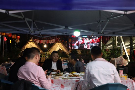 烧烤店内顾客们边吃烧烤边看比赛