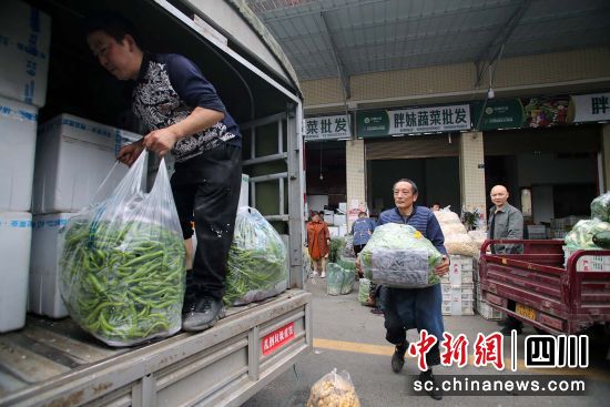 蔬菜批發(fā)商將新鮮蔬菜搬運(yùn)上車 王磊 攝
