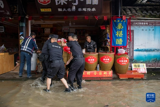10月5日，嘉陵江水漫进阆中古城内多条街道，公安民警帮助商户转运物资。