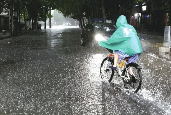 7月11日,成都市民在风雨中出行。