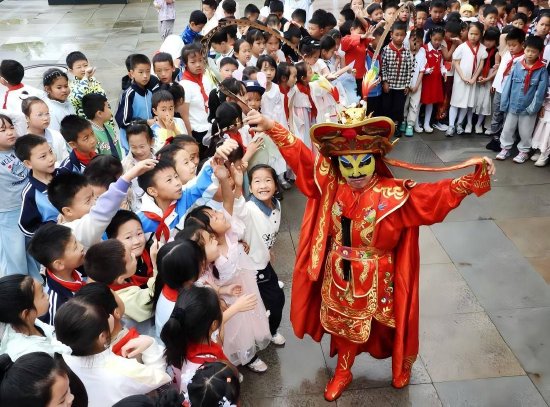 5月29日，四川省达州市达川区实验小学杨柳校区举行迎“六一”文艺汇演上，川剧变脸演员与观演的学生们互动。 邓良奎/摄