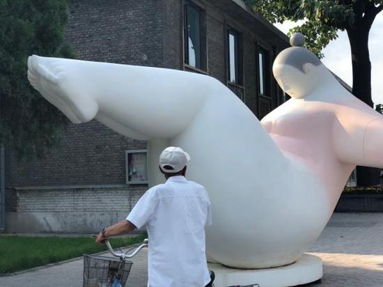 一位平遥当地老人走过室外雕塑作品前
