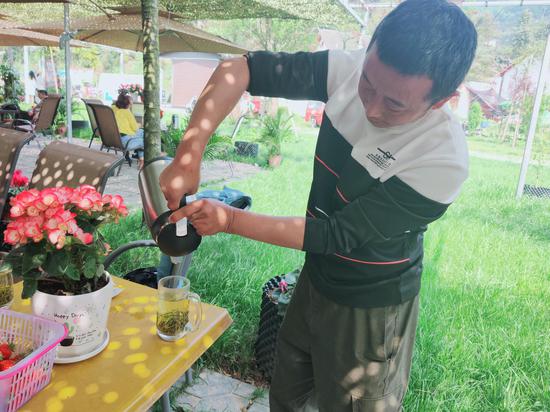 張發平為來農莊的游客倒茶。