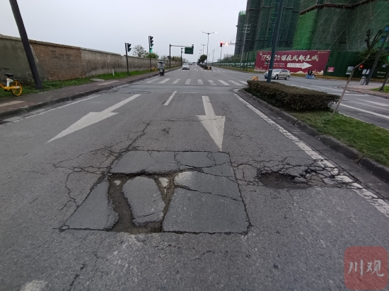 道路路面损毁，旁边存在较深的小坑