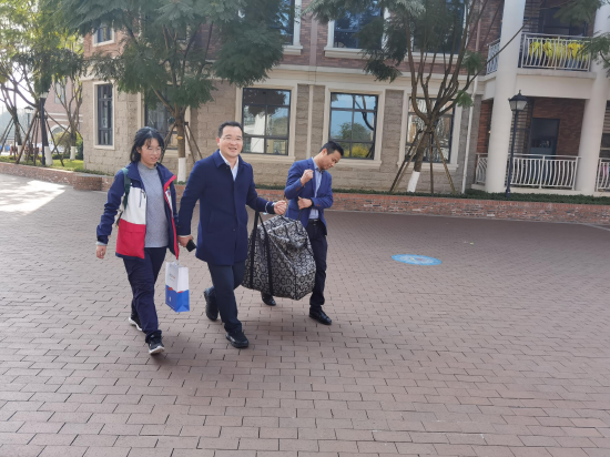 新川外国语学校董事长陈星海帮学生提行李
