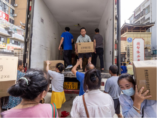 车民小学物资发放点的受灾群众帮助卸货。