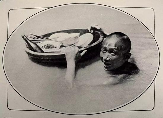 在逆境中仍安然自若:一个运送食品的苦力站在淹到脖子的深水区里。