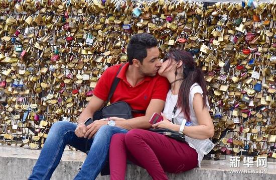 8月3日，在法国巴黎，一对恋人在桥栏挂满“同心锁”的新桥上热吻。