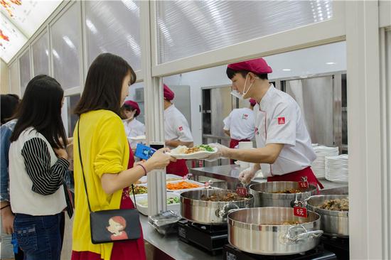 近日,四川大学锦江学院学生食堂华丽升级,化身吃货们的梦幻天堂。学生直呼食堂太美,吃饭要考虑穿着! 四川大学锦江学院学生食堂包含小炒区、风味菜品区、面包区、水果区、休闲区等多个功能区域。15个全国风味菜品窗口,让师生在学校就能用舌尖游览中国。食堂用餐环境一流,中央空调、WiFi齐备,温馨舒适的卡座、软座更是师生交流的首选。 明厨亮灶设计是四川大学锦江学院学生食堂的一大亮点。师生在窗口外就能看见后厨情况和菜品制作过程,这对后厨的清洁卫生提出了极高要求。五星级酒店餐厅标准配备的专业后厨设备,更是为