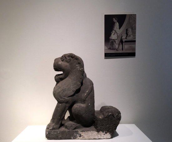 　　北魏大型灰色石狮在预展现场（背后附有“北魏大型灰色石狮与卢芹斋（Ching Tsai Loo 1880-1957）之女”照片），图片来源：99艺术网 杭亚
