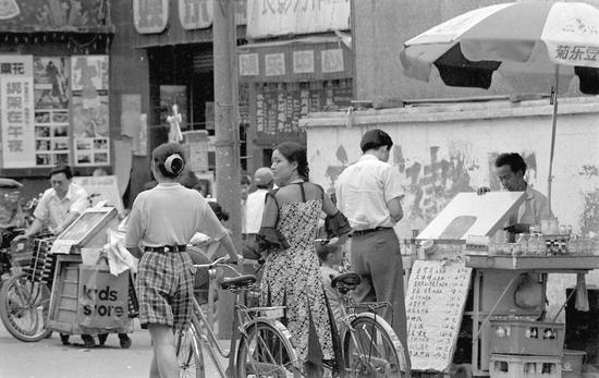 1994年,两个女子推自行车走过电影院门口。 刘陈平摄