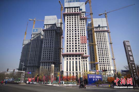 资料图 山西太原民众从一在建商业楼盘前经过。中新社记者 张云 摄