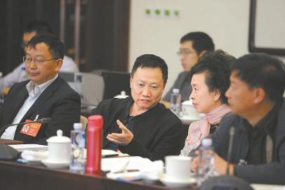 郑学炳委员(左)就促进矿产资源有序开发话题与其他委员交流意见。
